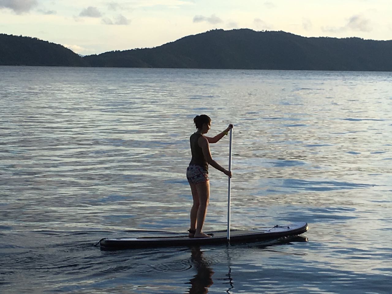 woman on a standup paddleboard with Raja Ampat islands in the background