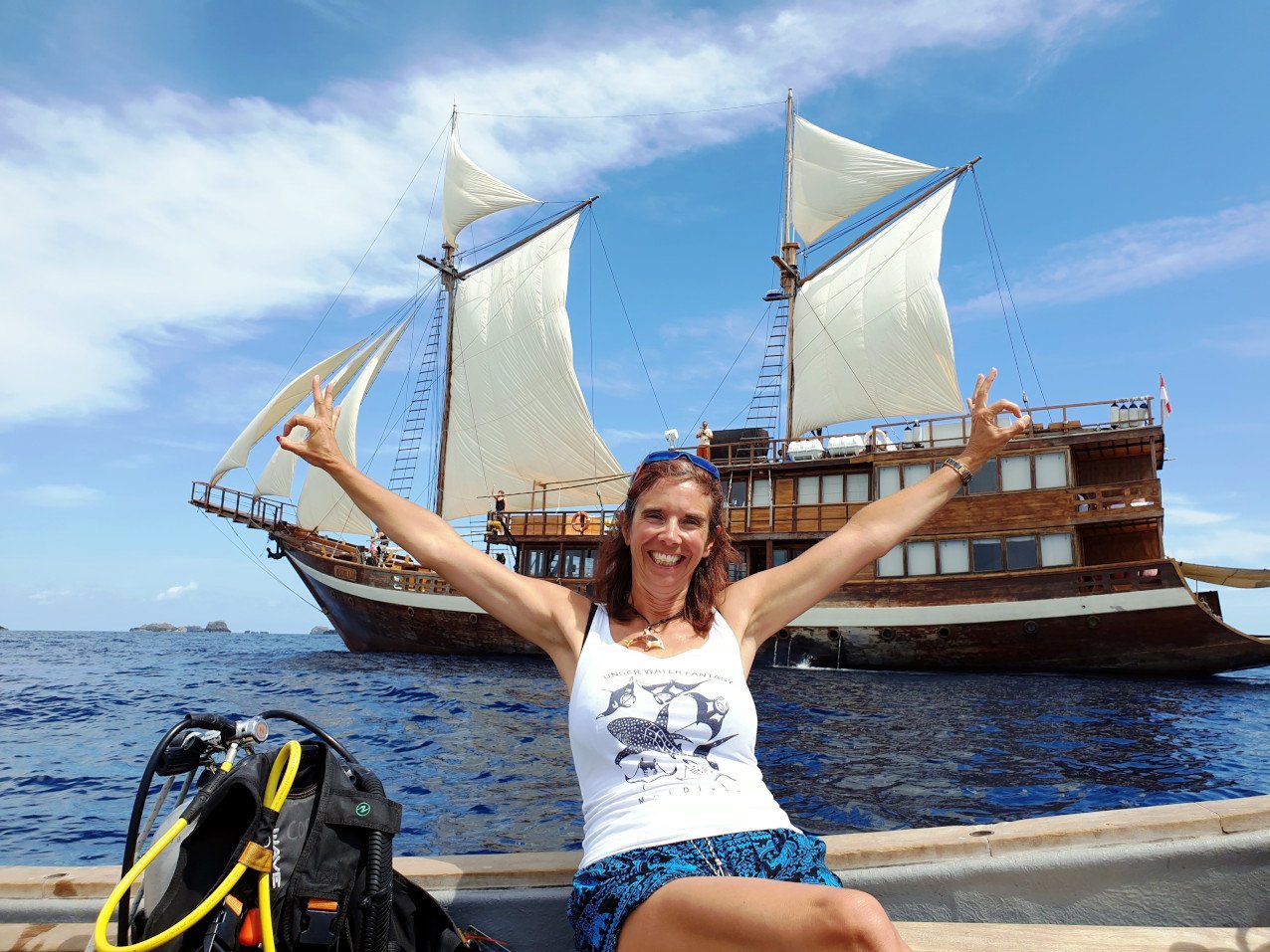 Papua Explorers Guest Gabby sitting on the tender with Coralia Liveaboard in the background