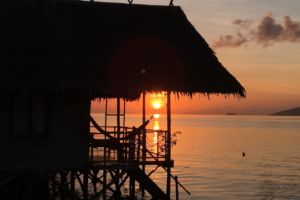 sun rising below the roof of a bungalow