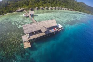 the dive centre building of Papua Explorers in an aerial shot with the water bungalows in the background