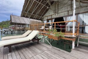 sunloungers and red umbrella and a wooden papuan statuse at our dive centre facing the ocean