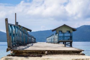 blue painted wooden jetty with two huts on the sides close to Papua Explorers Dive Resort