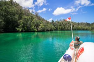 one of our guides sitting on the front of our excursion boat looking out over the sea and rainforest