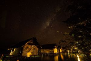 star-filled firmament above the well lit over water cottages of our Raja Ampat dive resort