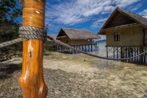 (English) view of our water bungalows in our resort in Raja Ampat with a tiny gekko sitting on a jetty pillar in the front