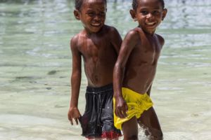 (English) two local boys of Raja Ampat in swim shorts plashing in shallow water close to Papua Explorers Dive Resort