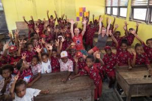 classroom filled with local students wearing red batik school uniform at the neighbouring village of Papua Explorers Dive Resort